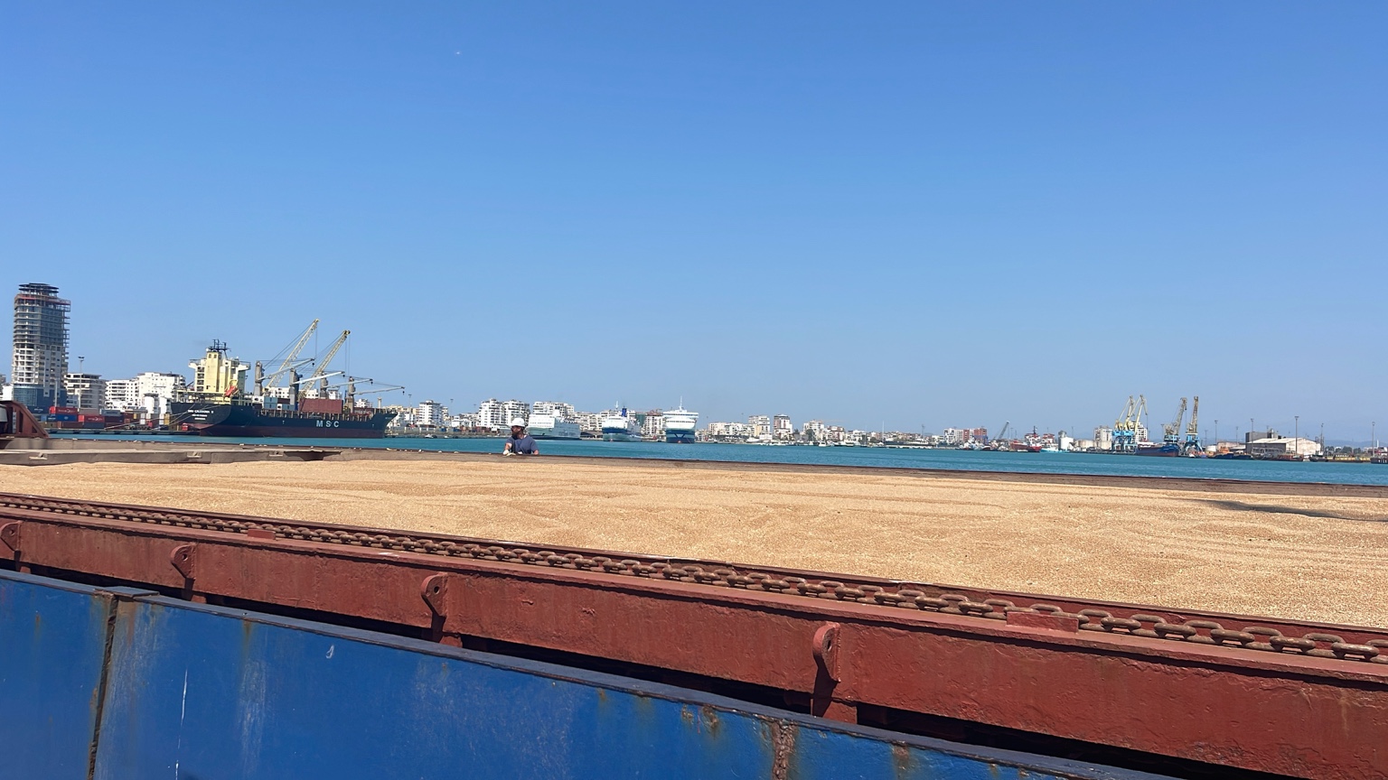 Bulk grain in an open vessel hold with the port in the background